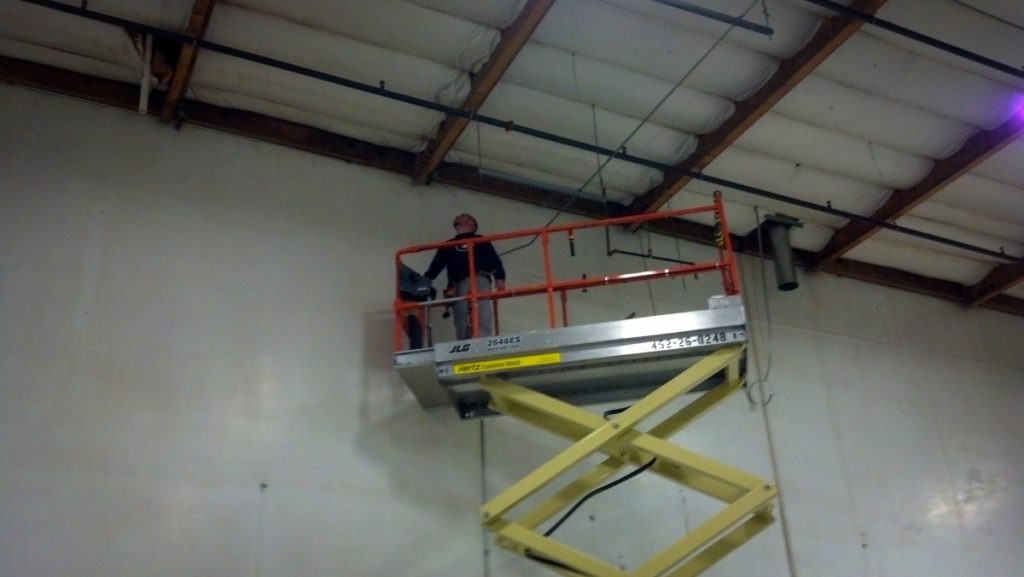 A Major Alarm technician installing devices from a scissor lift at the Redwood Empire Food Bank